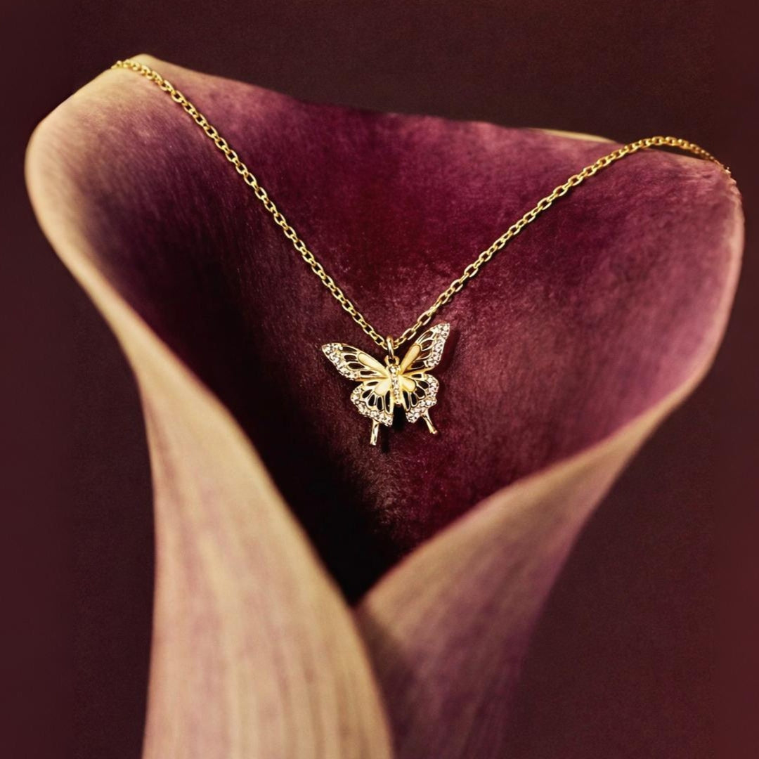 Gold butterfly necklace on a purple flower